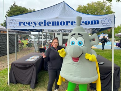 A person posing with a funnel shaped mascot in front of a booth