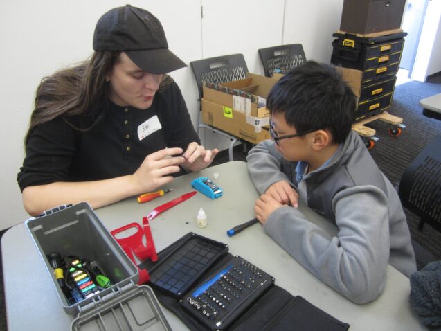 Fixit coach assisting a young resident with fixing an item with tools. 