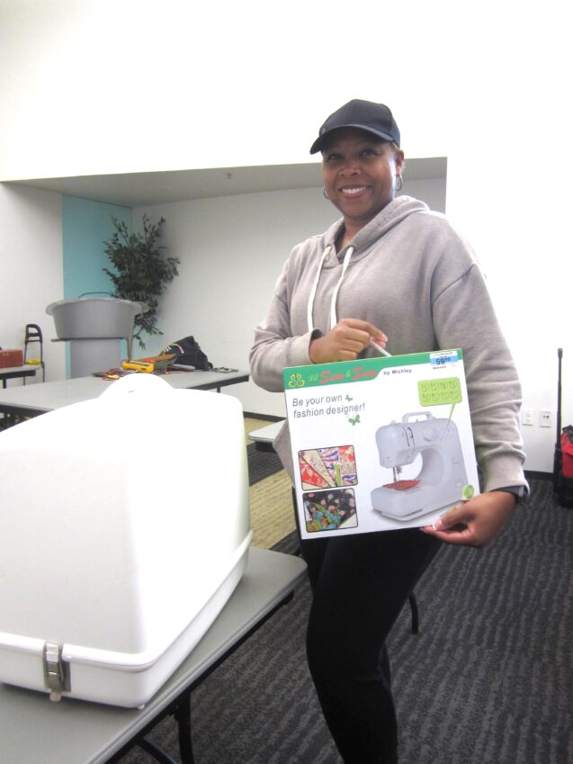 A smiling woman holding sewing machine box