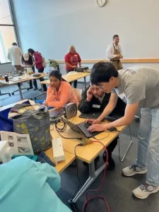A man bent over a desk typing on a laptop computer