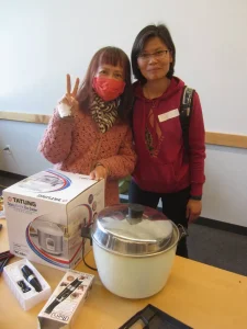 Two ladies behind cookware items on desk